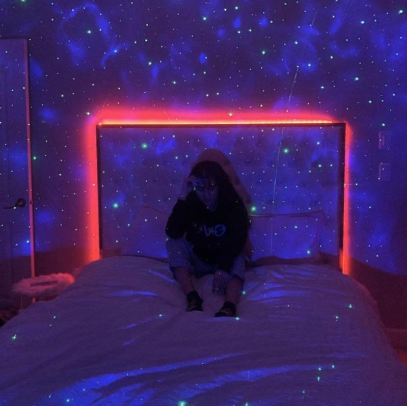 Kinderkamer met muurdecoratie en kleurrijke lichtprojectie van een sterrenhemel lamp.